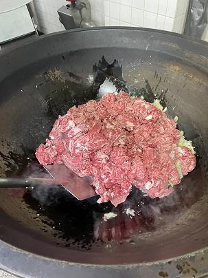 写真:大きな鍋で調理される肉