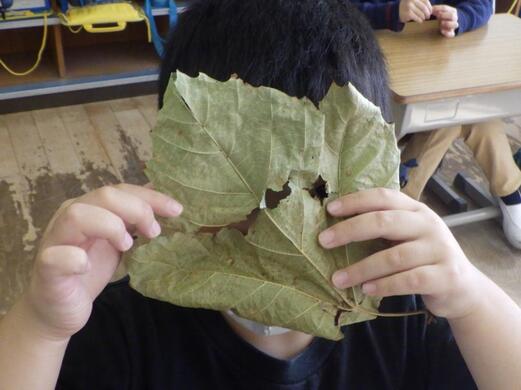写真:大きな葉っぱをお面にする生徒