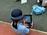 写真:外でタブレットPCを操作する子ども