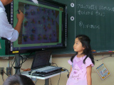 写真:電子黒板を見る先生と子ども