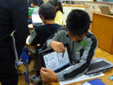 写真:タブレットPCを見せながら説明する子ども