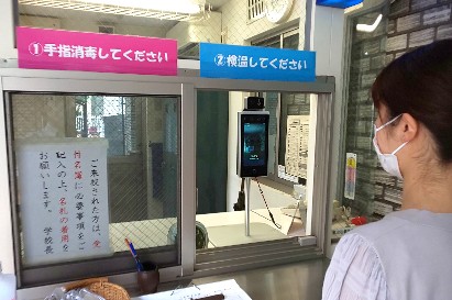 写真:「体表温度測定器」で検温している様子1