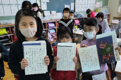 写真:硬筆書き初めを持った子どもたち