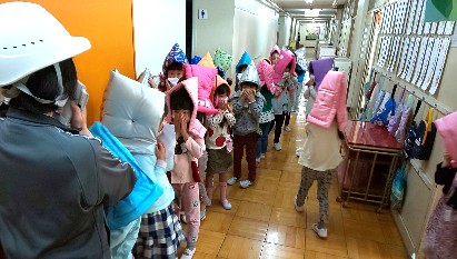 写真:防災頭巾をかぶり廊下に整列した1年生