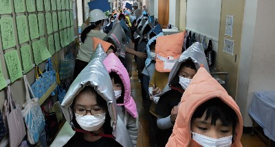 写真:防災頭巾をかぶり避難する様子