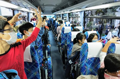 写真:バスの中から手を振る様子