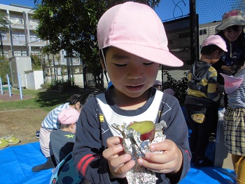 写真:アルミホイルに包まれた焼き芋を食べる子どもたち