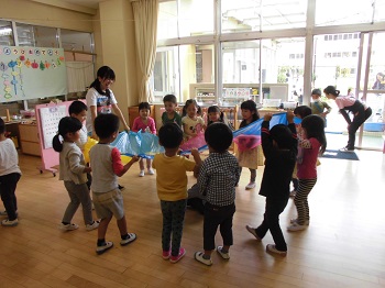 写真:カラフルな布をみんなで持つ子どもたち