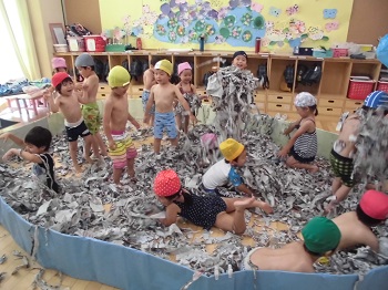 写真:水着を着て新聞プールを楽しむ子どもたち