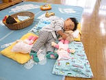 写真:赤ちゃんのお人形と一緒に寝ている子ども