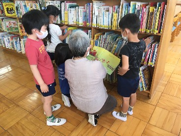 写真:本を見る先生と子どもたち