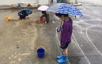 写真:バケツに水をためる子どもたち