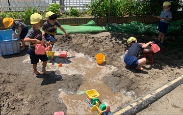 写真:水を使って砂場遊びをする子どもたち