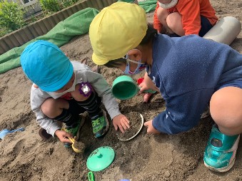 写真:道具を使って砂場で遊ぶ子どもたち