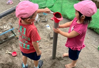 写真:細長い管に砂を注ぐ子どもたち
