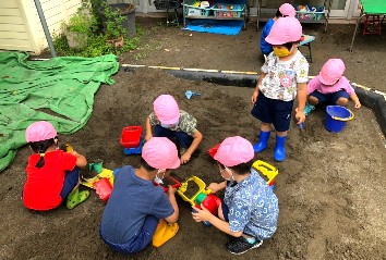 写真:庭に出て砂で遊ぶ子どもたち