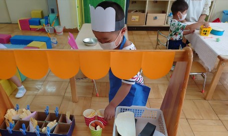 写真:帽子やエプロンを身につけ遊ぶ子どもたち