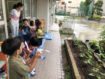 写真:てるてる坊主を持ってお願いする子どもたち