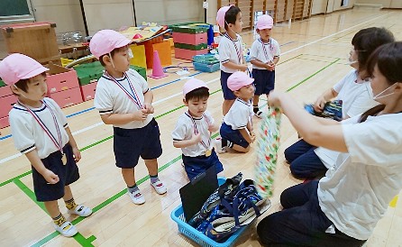 写真:プレゼントを渡す先生と子どもたち