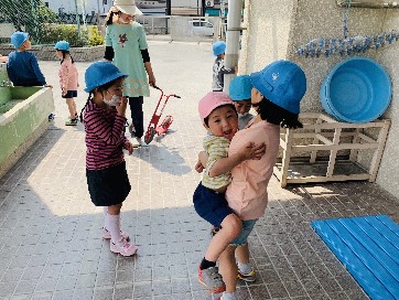 写真:遊びに来たお姉さんに抱っこしてもらう子ども