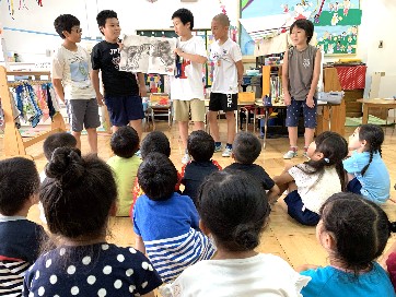 写真:お兄さんたちの絵本の読み聞かせを聞く子どもたち