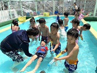 写真:水に浮いたり水鉄砲をする子どもたち