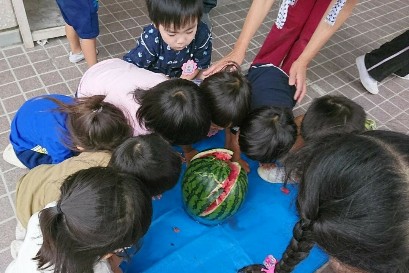 写真:割れたスイカを見る子どもたち