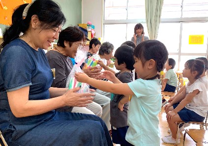 写真:おじいちゃんとおばあちゃんにプレゼントを渡す子どもたち