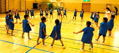 写真:青い衣装を着て輪になって練習する子どもたち