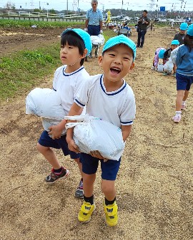 写真:お芋を運んで笑顔の子どもたち
