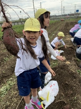 写真:サツマイモを持って笑顔の子どもたち