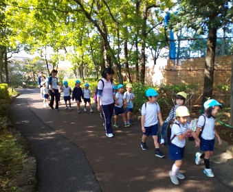 写真:公園の木々の下を歩く子どもたち