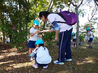 写真:支援員さんとどんぐりの選別をする子どもたち