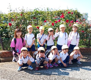写真:きれいに咲くバラ園でピースをする子どもたち