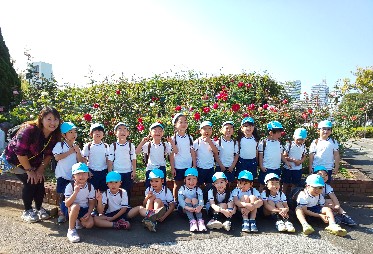 写真:バラの前に並ぶ子どもたちと先生
