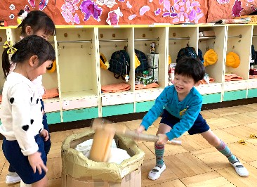 写真:手作りの臼と杵を使ってお餅つきをする子どもたち