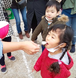 写真:ふかしたもち米を食べる子どもたち