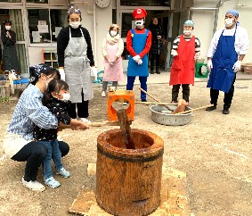 写真:大人と一緒に餅をつく子ども1