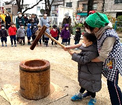 写真:大人と一緒に餅をつく子ども2