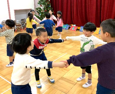 写真:手をつないでジングルベルのダンスを踊る子どもたち