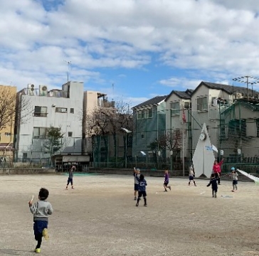 写真:青空の下で凧を持って走る子どもたち