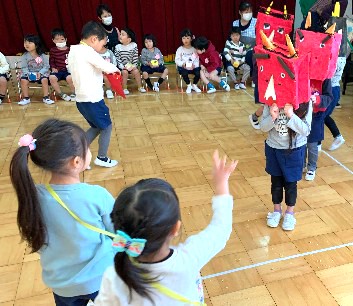 写真:鬼のお面をかぶった年長組さんと椅子に座る子どもたち