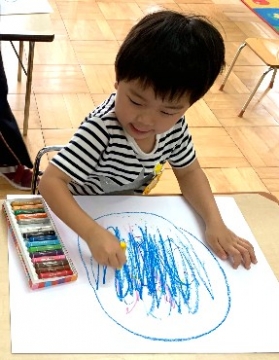 写真:青色のクレヨンで絵を描く子ども