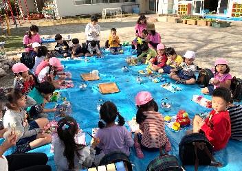 写真:庭でお弁当を食べる子どもたち