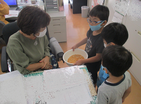 写真:園長先生にトウモロコシの粒を見せている子どもたち