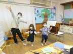 写真:手を広げて踊る先生と子どもたち