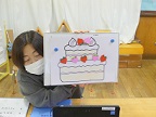 写真:ケーキの絵を見せる先生