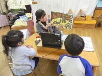 写真:絵本を読む先生と子どもたち