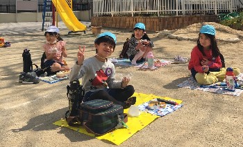 写真:心地よい天気の中でお弁当を食べる子どもたち