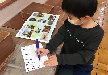 写真:本を見ながら文字を書く子ども